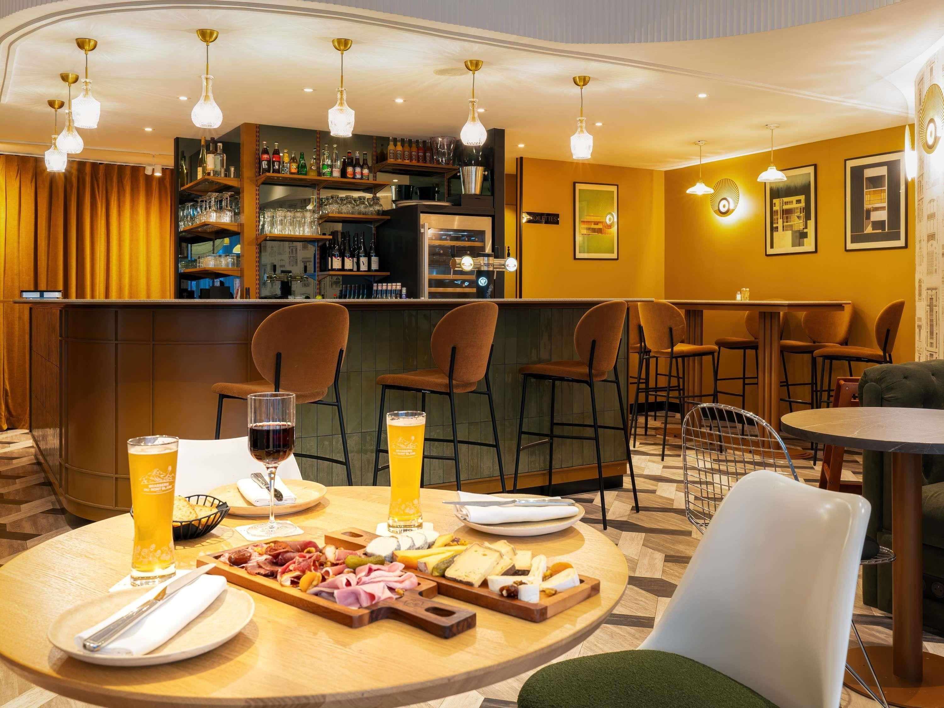 Una zona de bar con una mesa redonda, sillas y una variedad de bebidas y aperitivos.