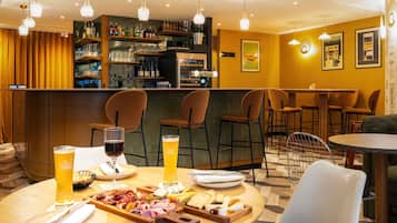 Una zona de bar con una mesa redonda, sillas y una variedad de bebidas y aperitivos.