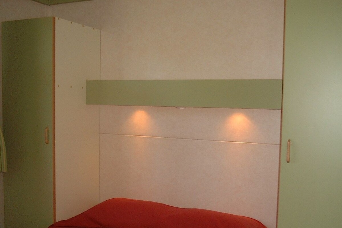 Una habitación con una cama, paredes verdes y techo blanco.