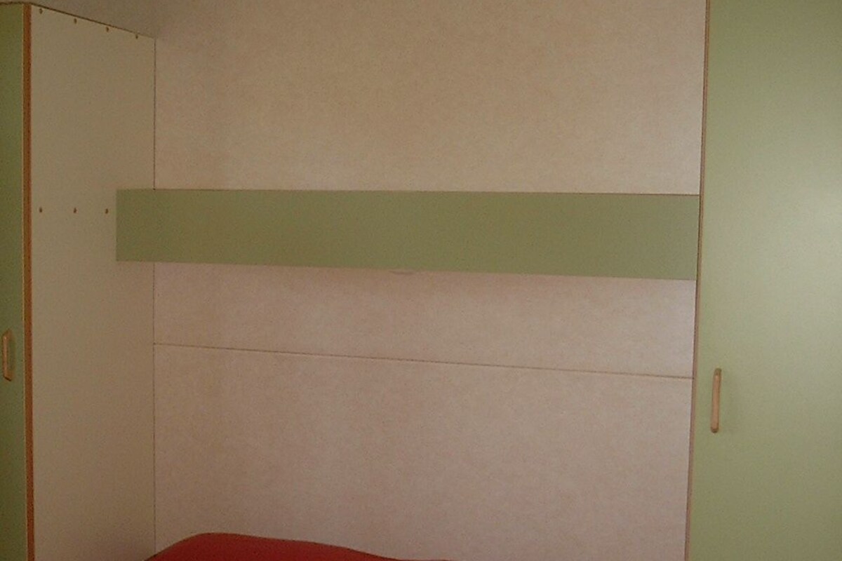Una habitación con literas, paredes verdes y una sola puerta.