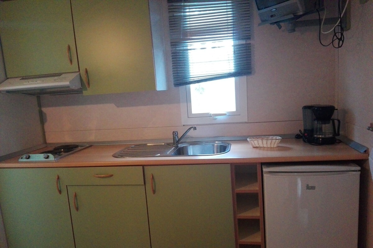 Cocina compacta con lavamanos, estufa y refrigerador pequeño.