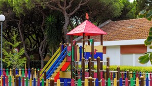 Un parc infantil amb jocs de colors i una zona coberta amb teulada vermella.