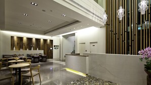 Un hall d’hôtel moderne comprenant un comptoir d’accueil, un espace salon et un mur décoratif agrémenté de lambris en bois verticaux.