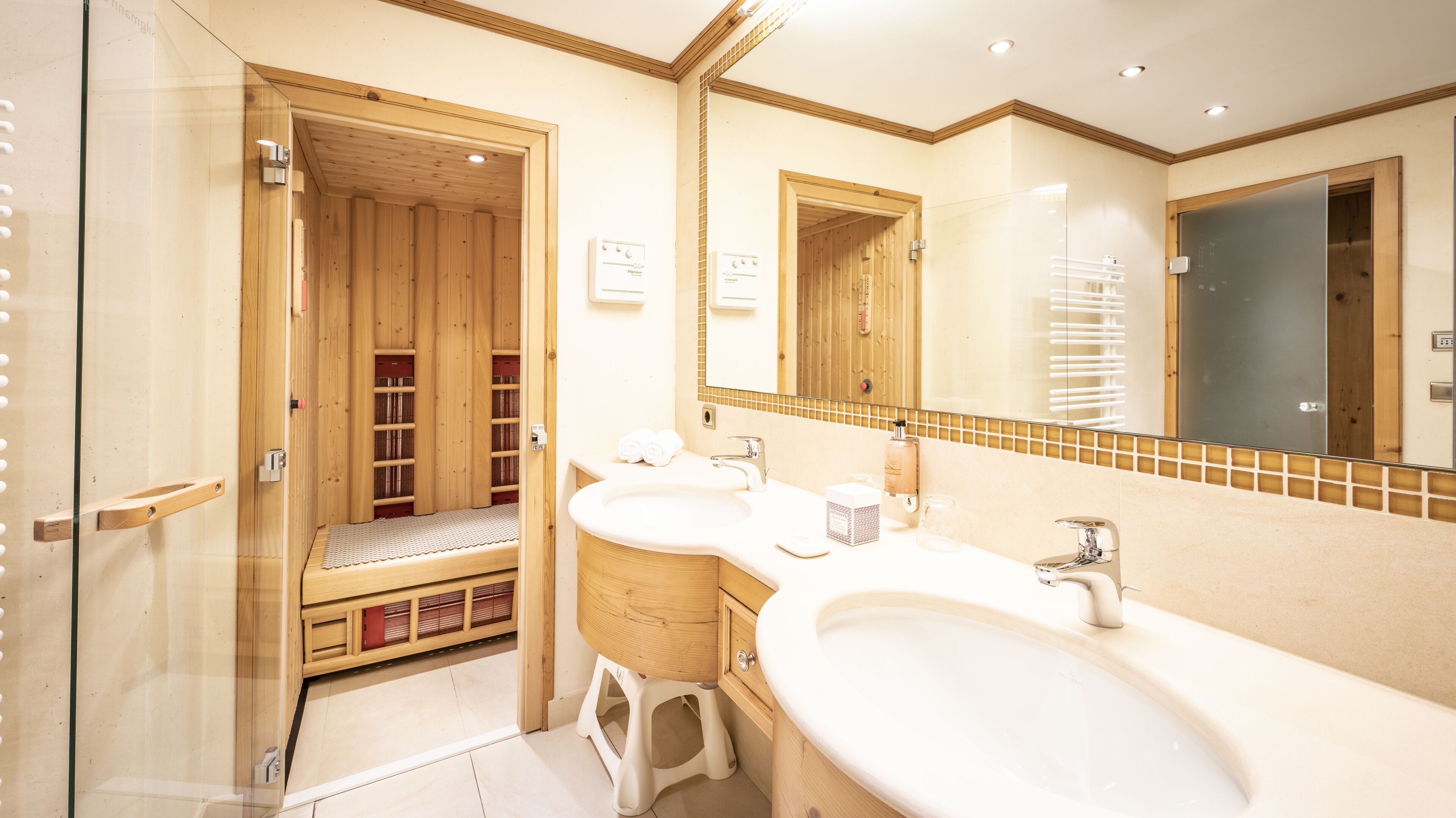 A bathroom with a wooden sauna, two sinks, and a large mirror.