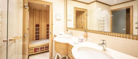 A bathroom with a wooden sauna, two sinks, and a large mirror.