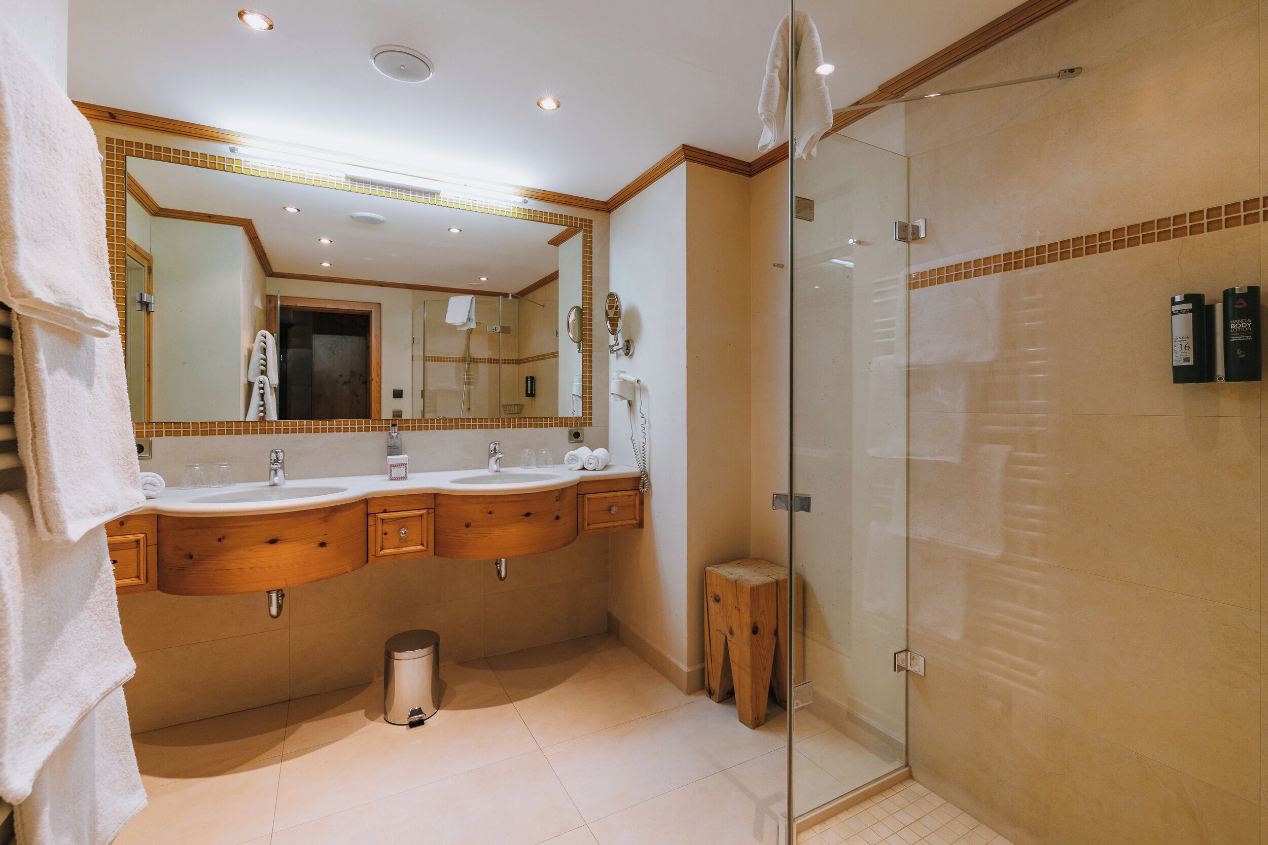 A modern bathroom with two sinks, a glass shower enclosure, and a vanity with a mirror.