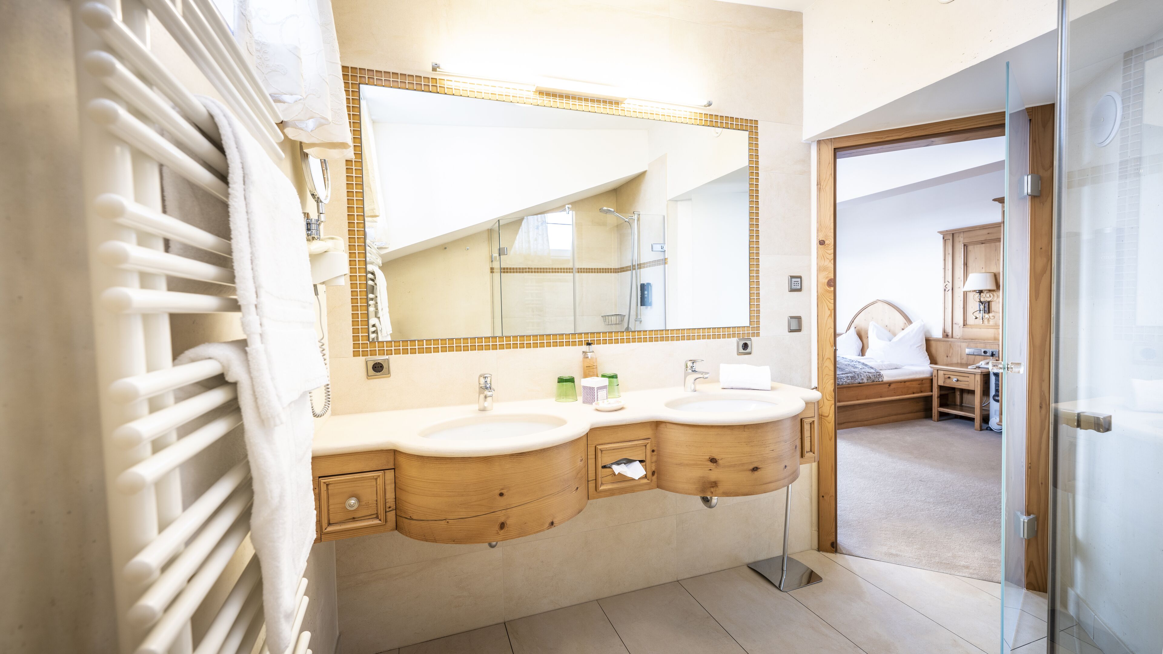 A bathroom with two sinks, a large mirror, and a glass shower enclosure.