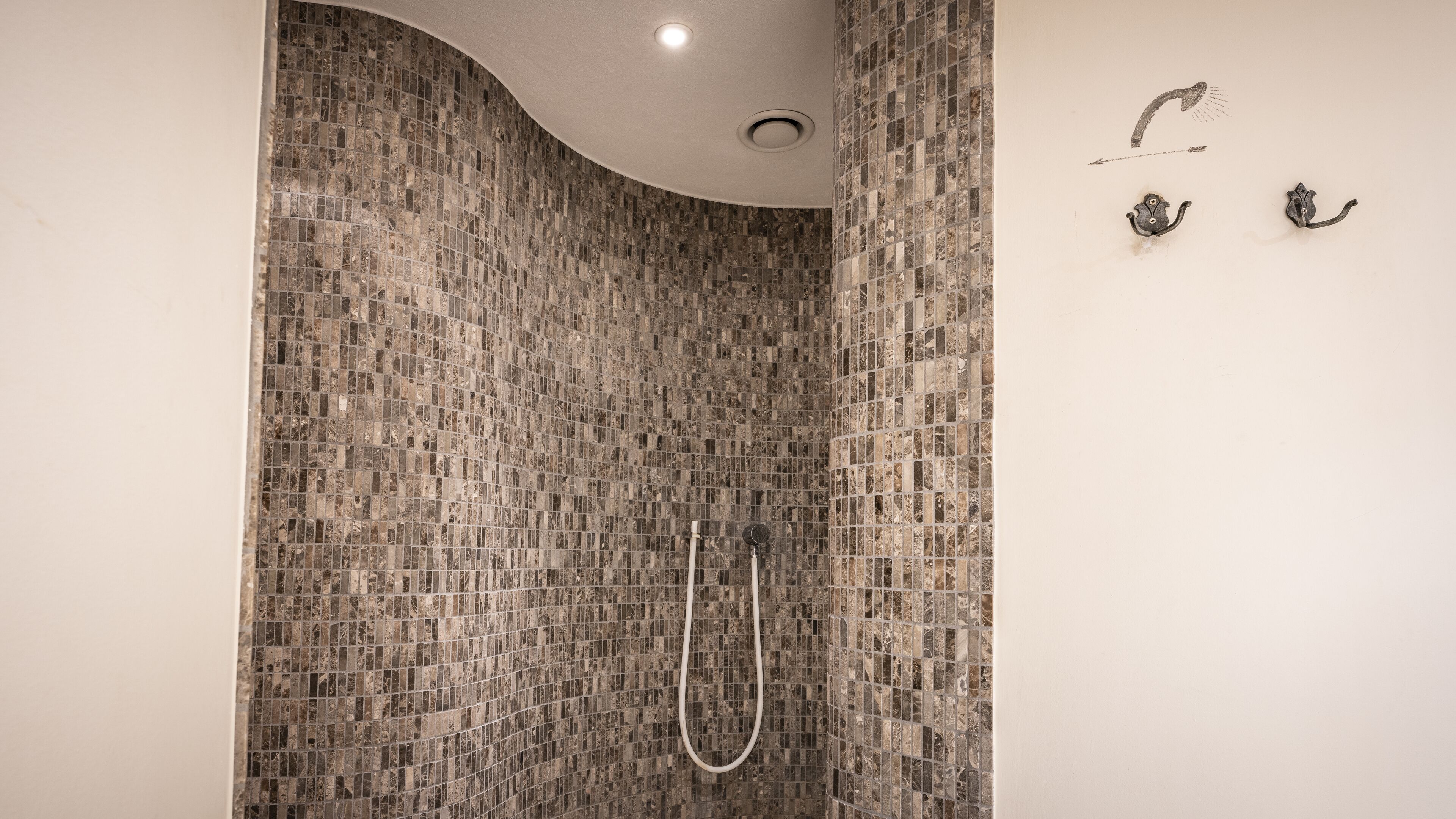 Une douche dont les murs sont recouverts de mosaïques et dont le plafond est incurvé.