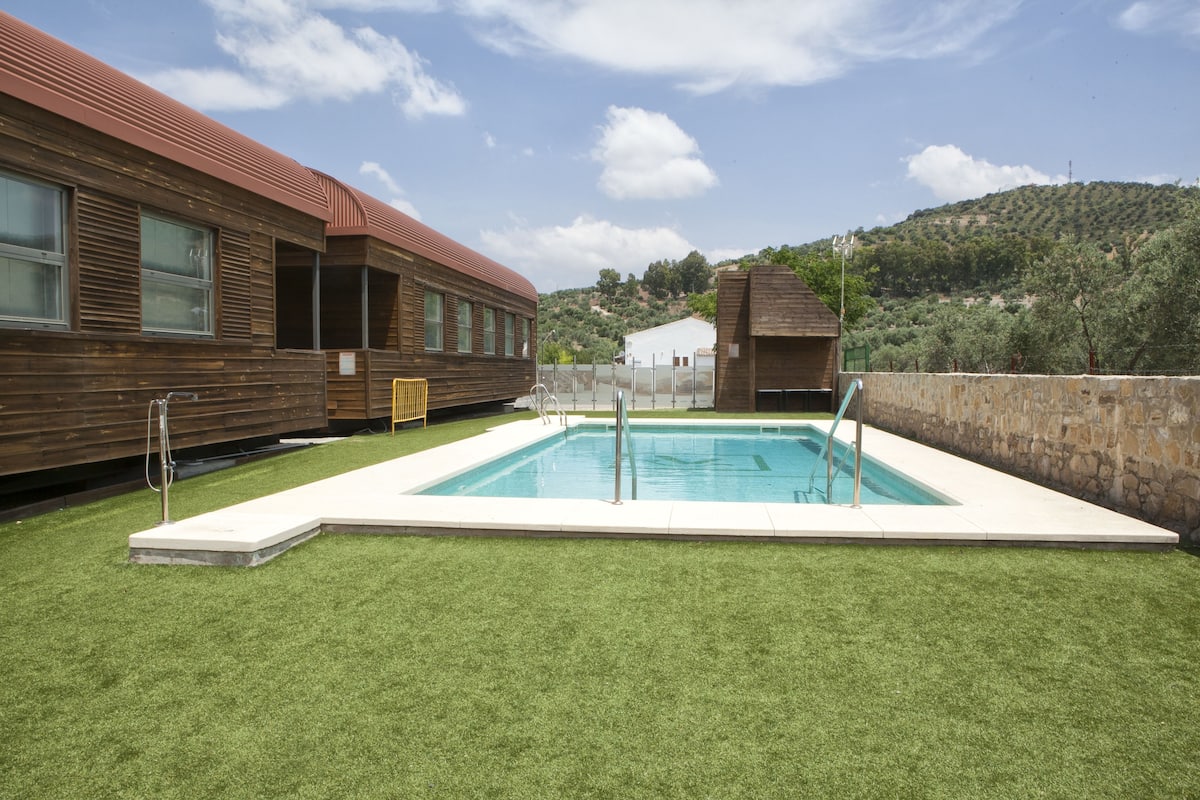 Un área de piscina con un edificio de madera y una pared de piedra.