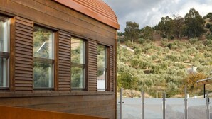 A modern building with a sloped roof and large windows. - Casa Vagón Vía Verde Sierra (Olvera)