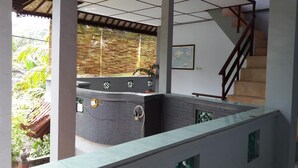 A modern interior with a kitchen area, a staircase, and a view of greenery outside. - Celagi Inn (Padangbai)