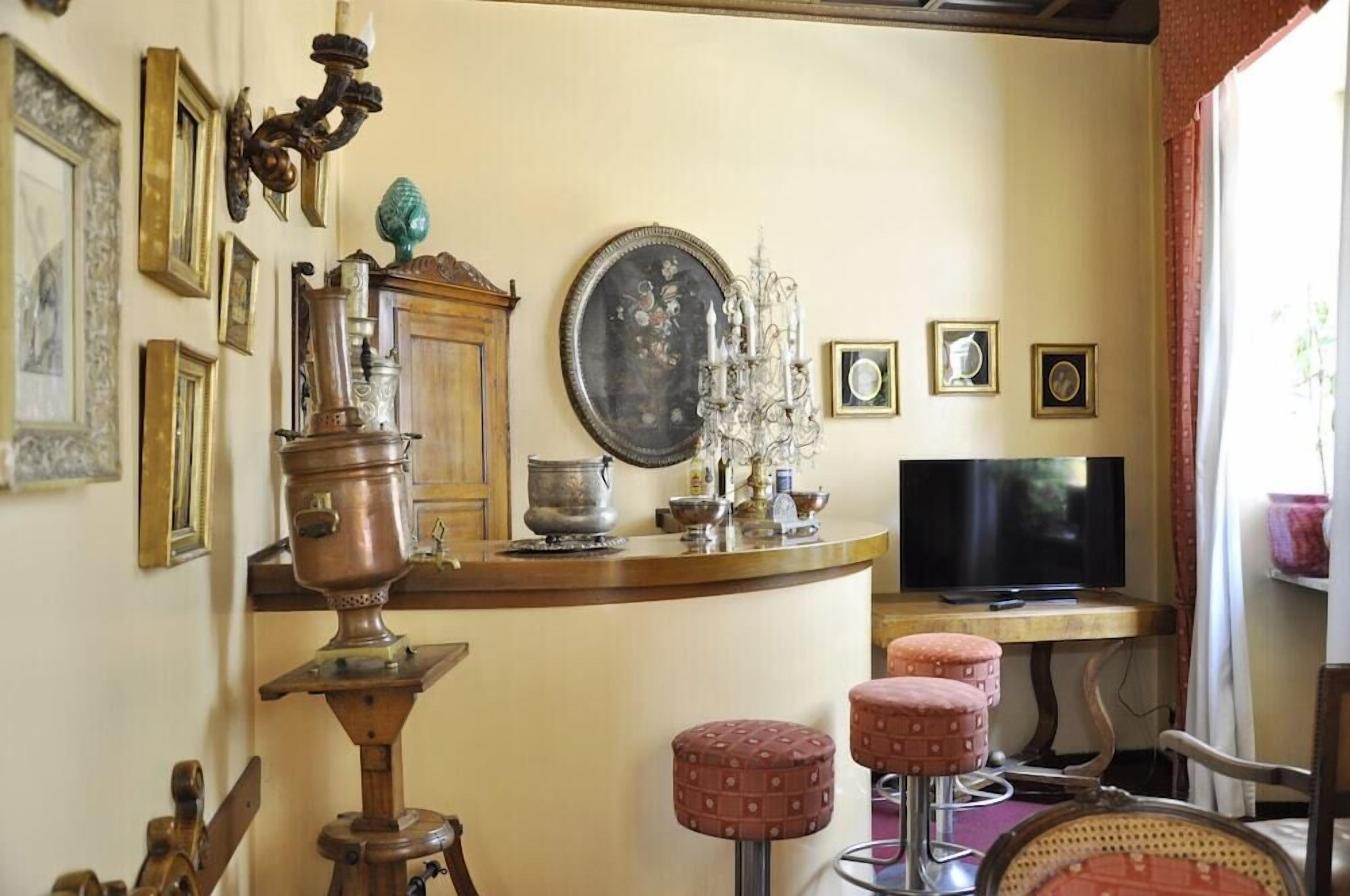 A room with a wooden bar counter, a television, and a chandelier.