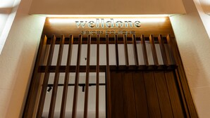 Una entrada bien diseñada con un portón de listones de madera y señalización iluminada para 'welldone sierpes boutique'.