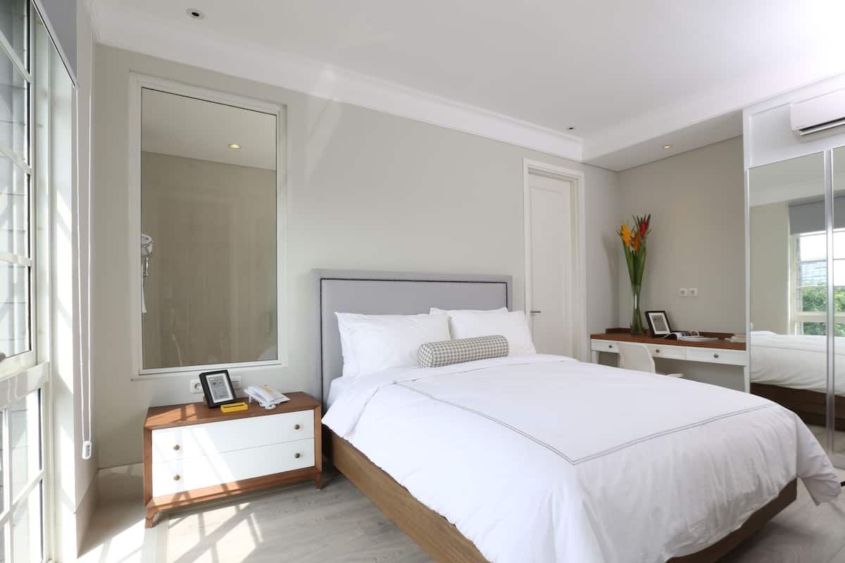 A modern bedroom with a large bed, bedside table, and a mirror.
