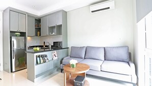 A modern kitchen with grey cabinets, a built-in oven, and a coffee table with a vase. - Havenwood Residence TB Simatupang (Jakarta)