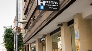 Une enseigne d’hôtel indiquant « Hostal Verona », avec un symbole de stationnement, signalant la présence d’un parking sur place.