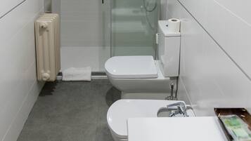 Un baño moderno con ducha de vidrio, inodoro y lavamanos.