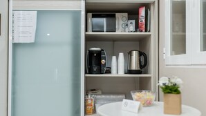 Une petite cuisine équipée d’un réfrigérateur, d’un four à micro-ondes, d’une machine à café et de divers produits alimentaires.