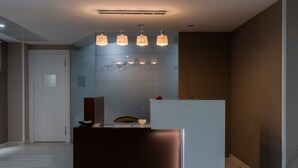 Une cuisine moderne avec un plan de travail foncé, un réfrigérateur blanc et des luminaires suspendus.