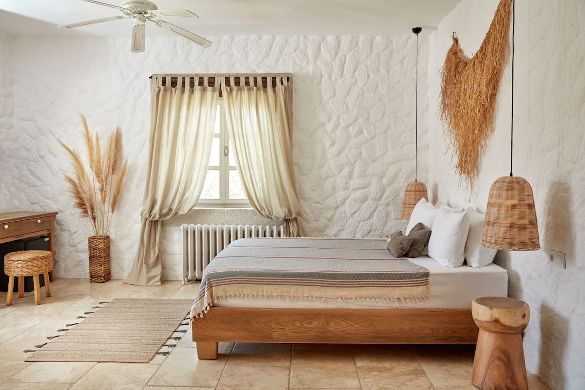 Ein Schlafzimmer mit einem hölzernen Bett, einem Schreibtisch, einem Heizkörper und einem Fenster mit Vorhängen.