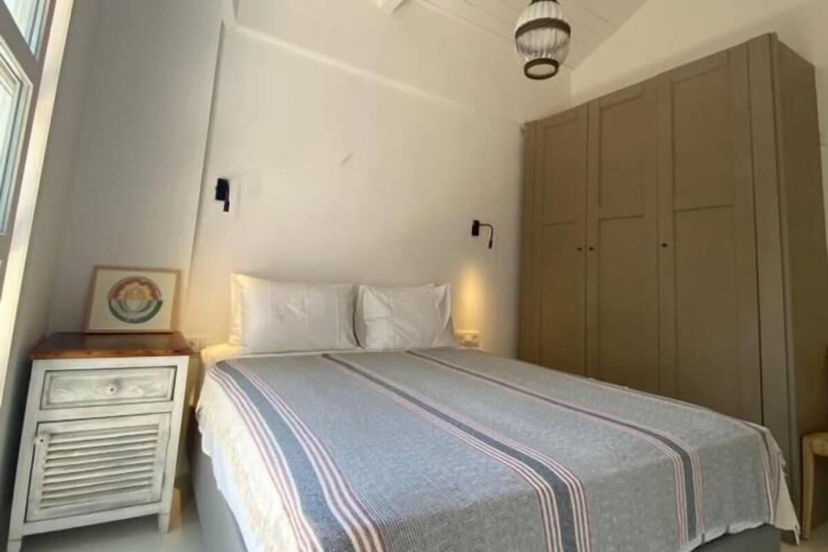 Ein Schlafzimmer mit einem Bett, Nachttischen, einem Kleiderschrank und einer Pendelleuchte.