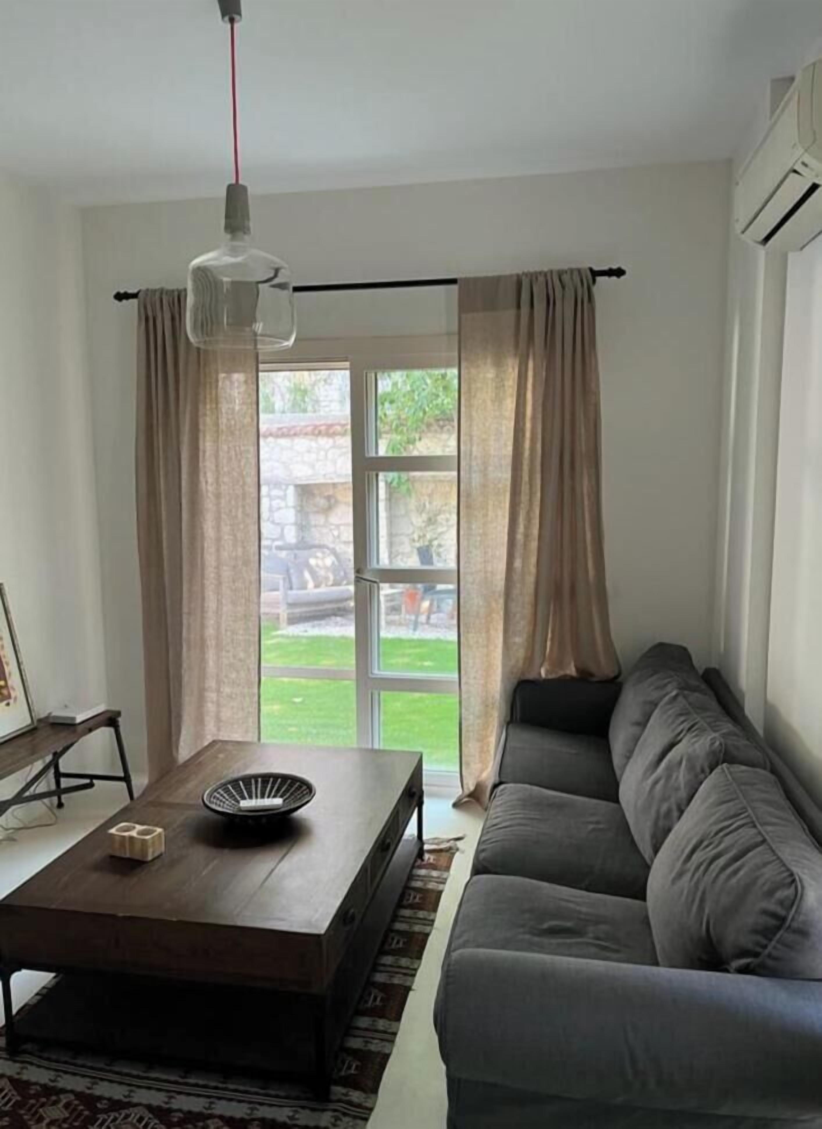 A living room with a sofa, a coffee table, and a hanging light fixture.