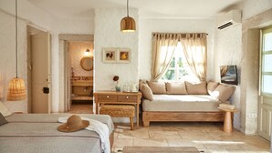 Ein Schlafzimmer mit einem Bett, einem Nachttisch, einer kleinen Couch, einem Spiegel und einem Fenster mit Vorhängen.