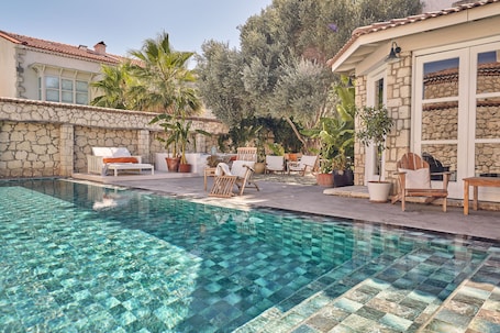 Una piscina al aire libre, sombrillas, sillones reclinables de piscina