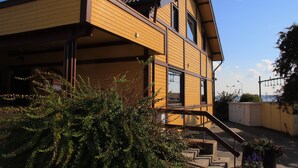 Una casa moderna de dos pisos con techo inclinado, ventanas grandes y una escalera visible que conduce a la entrada.