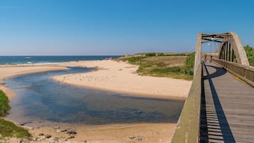 A wooden boardwalk leading to a sandy beach with a calm sea.