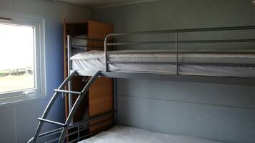 A bunk bed with a ladder, a window, and a wooden cabinet.