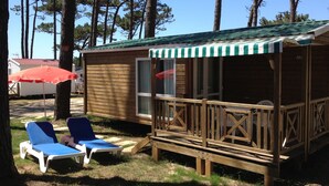 Una cabaña de madera con un porche, dos sillones de descanso y un paraguas rojo.