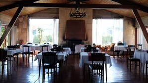 Un comedor amplio con varias mesas y sillas, ventanas grandes y techo de madera.