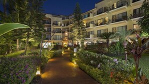 Ein Hotel mit mehreren Balkonen, einem gepflasterten Weg und üppiger Bepflanzung.