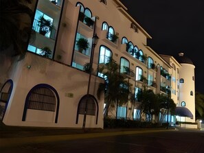 A multi-story hotel with arched windows and balconies, a dome-shaped structure on the right, and a well-lit facade. - The Hotel Flamingo Vallarta (PUERTO VALLARTA)
