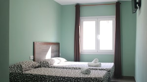 Une chambre avec deux lits, une fenêtre avec des rideaux et une tête de lit.