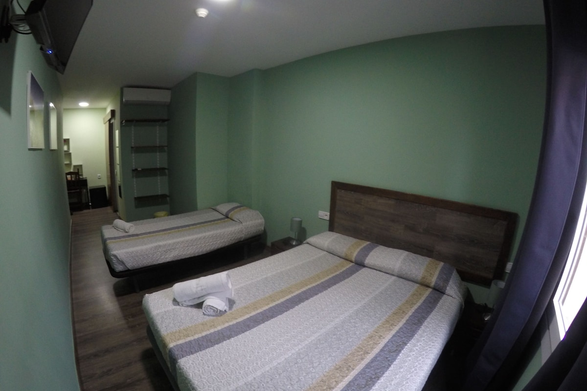 Une chambre d’hôtel avec deux lits, une tête de lit en bois et un petit bureau avec une chaise.