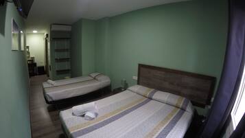 Hotellihuone, jossa on kaksi sänkyä, puinen pääty ja pieni työpöytä tuolilla.