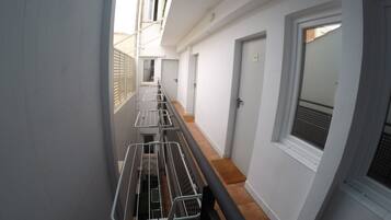 Un pasillo estrecho con tendederos metálicos, una puerta y una ventana con vistas al exterior.