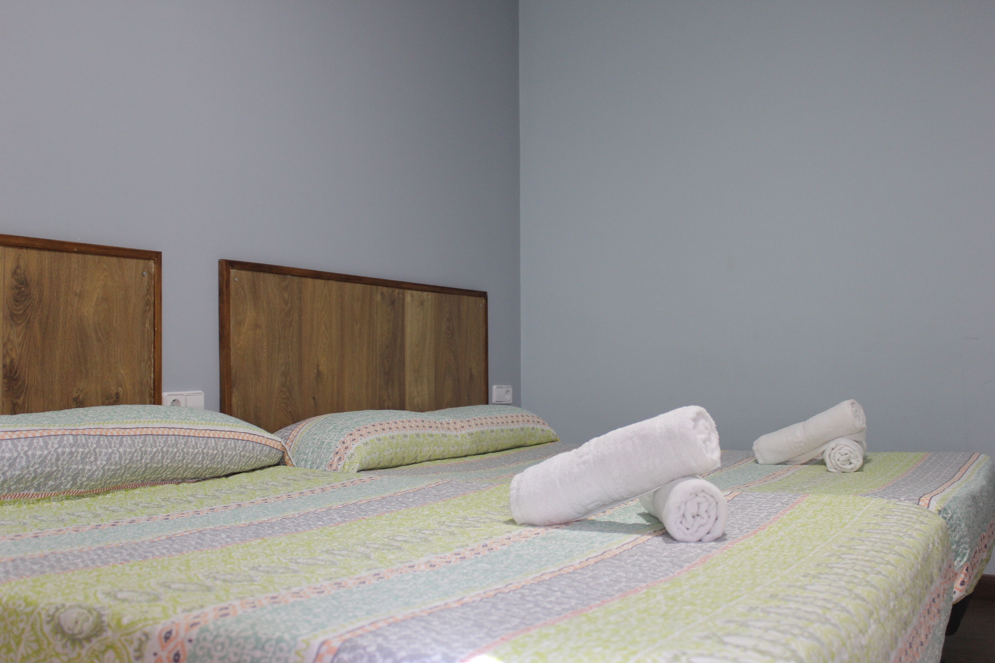 Une chambre d’hôtel avec un lit, une tête de lit en bois et un lit parfaitement fait, avec des serviettes pliées.