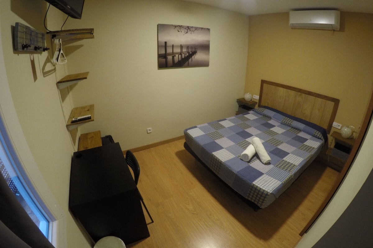 Une chambre à coucher avec un lit, un bureau, une chaise, une télévision et un tableau accroché au mur.