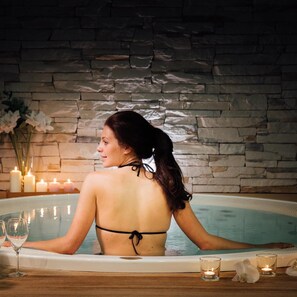 A woman in a bathtub with candles and flowers.