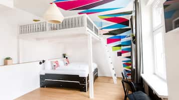 Cozy retreat with a bunk bed, desk area, and sloped ceiling featuring a geometric pattern.