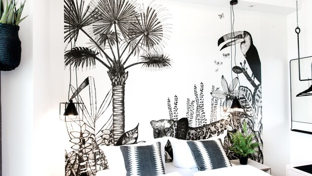 A bedroom with a bed, pillows, a hanging plant, and a wall mural. - Pyjama Park Schanzenviertel - Hostel (Hamburg)