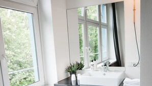 A modern bathroom with a large window, a white sink, and a mirror. - Pyjama Park Schanzenviertel - Hostel (Hamburg)