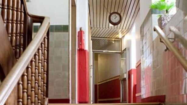A staircase with wooden handrails, a clock on the wall, and a red accent wall. - Smart Stay Hotel Station Munchen (Munich)