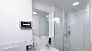 A modern bathroom with a glass shower enclosure, a white sink, and a built-in mirror. - Smart Stay Hotel Station Munchen (Munich)