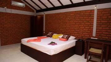 A bedroom with a brick wall, a bed with pillows, a bedside table, and an air conditioning unit.