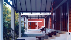 Un bâtiment moderne à la façade en briques rouges, aux murs extérieurs blancs et doté d’un espace extérieur couvert avec des marches menant à un banc en bois.