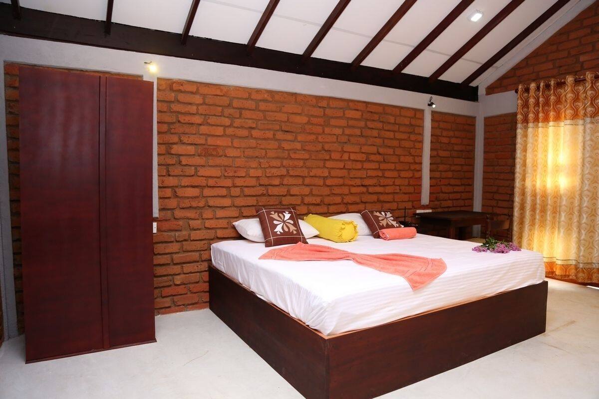 A bedroom with a brick wall, a wooden bed, and a wardrobe.